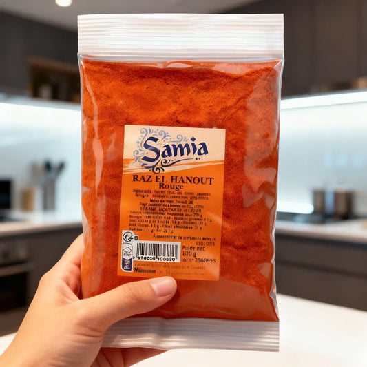 Main tenant un sachet de Raz el hanout rouge SAMIA, mélange d'épices riche pour plats traditionnels et recettes épicées.