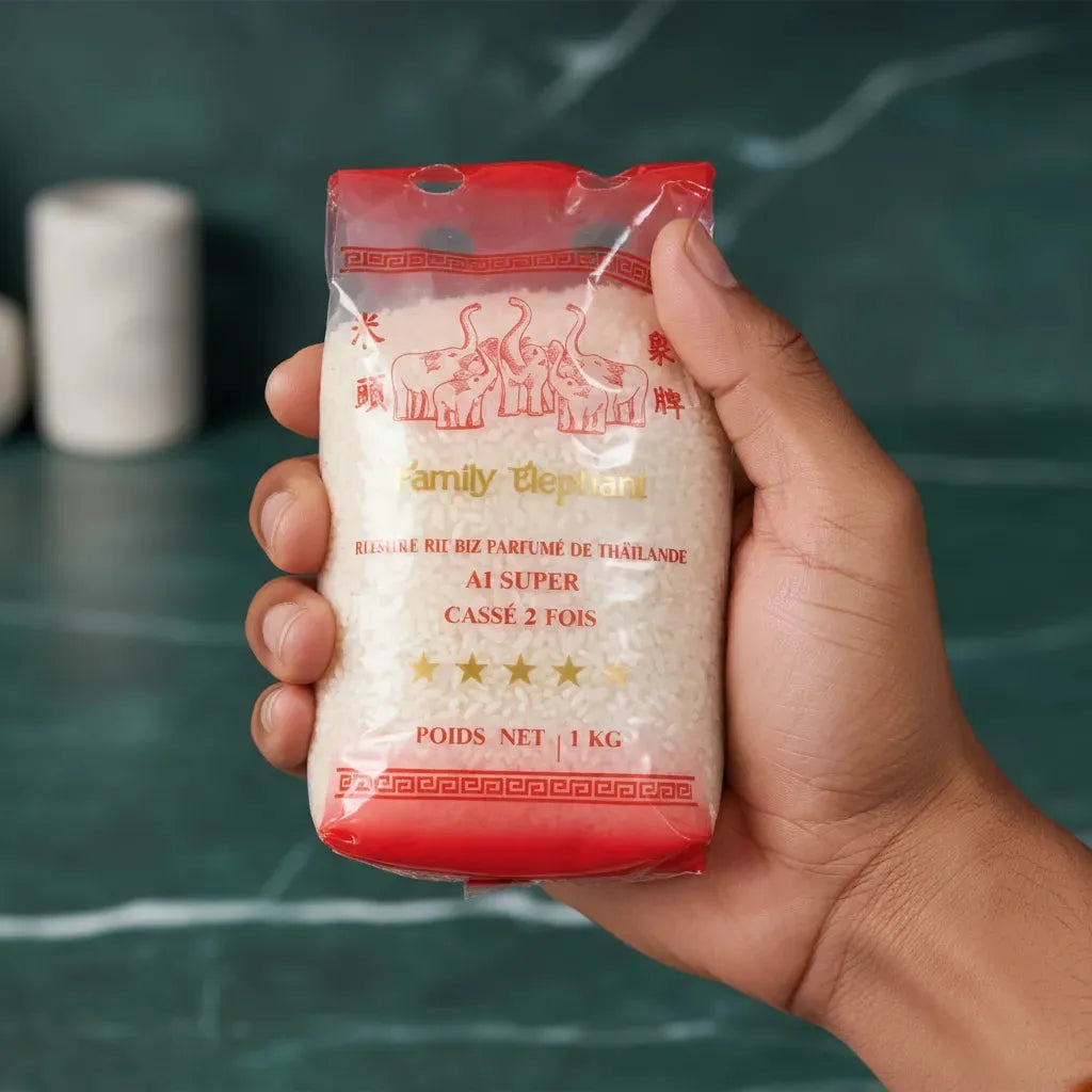 Main tenant un sachet de brisures de riz TERSOL cassé 2 fois Family Elephant 1 kg, parfait pour l'épicerie salée et les plats du quotidien.