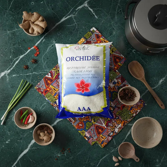 Sac de riz jasmin ORCHIDÉE entouré d'ingrédients asiatiques sur table verte. Riz cassé 1 fois idéal pour recettes authentiques.