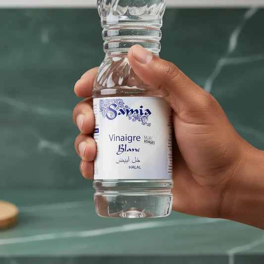 Main tenant une bouteille de vinaigre blanc halal SAMIA, condiment pur et polyvalent pour assaisonnement et nettoyage domestique.