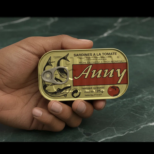 Main tenant une boîte de sardines à la tomate ANNY, produit pratique de l'épicerie salée, format compact 125g.