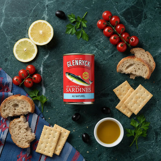 Sardines Glenryc naturelles entourées d'ingrédients frais comme citron, tomates et pain, parfaites pour une présentation culinaire en épicerie salée.
