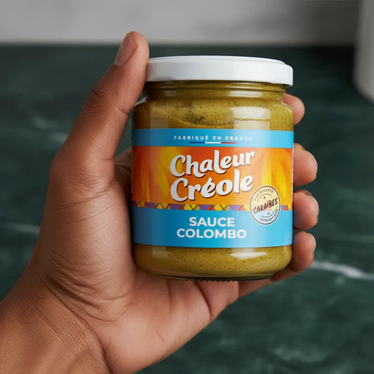Main tenant un pot de sauce colombo CHALEUR CREOLE, produit d’épicerie salée aux épices créoles, parfait pour recettes exotiques.
