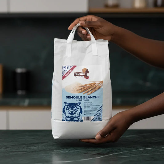 Main tenant un sac de semoule blanche TANTIE - Blé dur, Polyvalente, Fraîche, format 5 kg, pratique pour l'épicerie salée et pâtisserie.