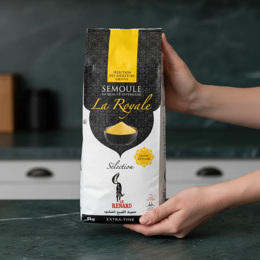 Main tenant un paquet de semoule RENARD Extra-fine La Royale 5kg, blé de qualité supérieure pour préparations culinaires homogènes et légères.