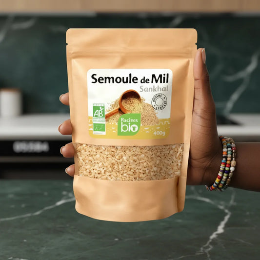 Main tenant un sachet de Semoule de Mil BIO RACINES 400g, parfait pour une alimentation riche et naturelle, certifiée bio.