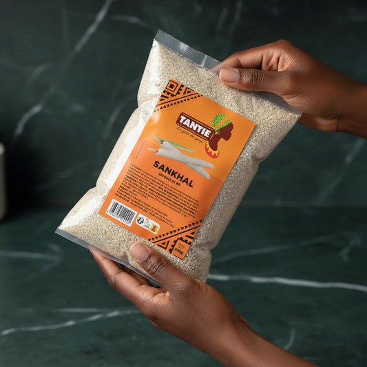 Main tenant un paquet de Sankhal TANTIE - Poisson Séché Fermenté, semoule de mil pour cuisine africaine, produit d'épicerie salée.