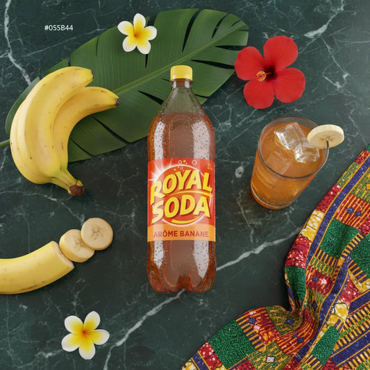 ROYAL SODA goût banane posé sur une table avec bananes, fleurs tropicales et tissu coloré, soda exotique parfait pour l'été.