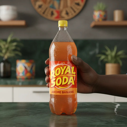 Main tenant une bouteille de ROYAL SODA goût banane dans une cuisine moderne, soda rafraîchissant au goût naturel de banane.