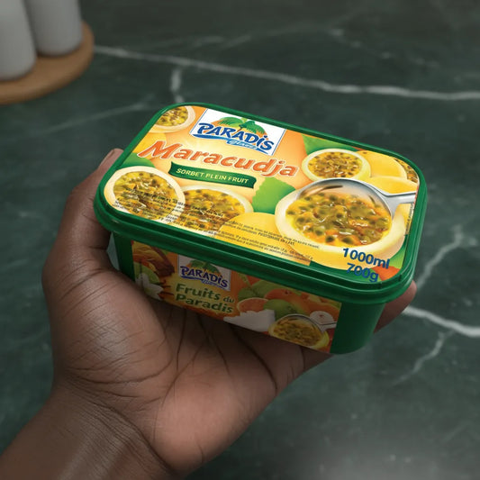 Main tenant un pot de glace Paradis Maracudja 700g, sorbet fruité à la passion, emballage coloré et pratique pour dessert exotique à emporter.