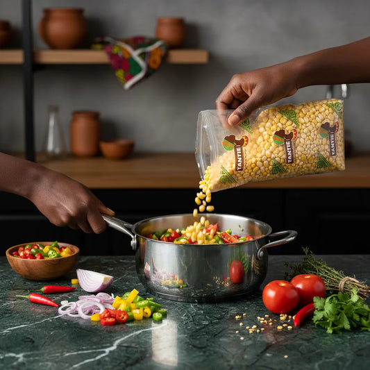 Utilisation du maïs dégermé jaune TANTIE en cuisine, versé dans une marmite avec légumes frais, idéal pour recettes savoureuses et nutritives.