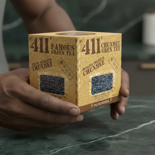 Main tenant une boîte de thé vert Chunmee 411, soulignant la qualité premium et l'emballage artisanal du produit.