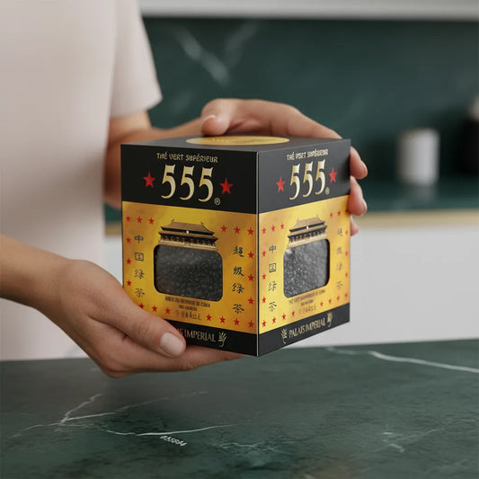 Boîte de thé vert Gunpowder Superextra 555 tenue à deux mains, packaging élégant pour thé en vrac de qualité supérieure.
