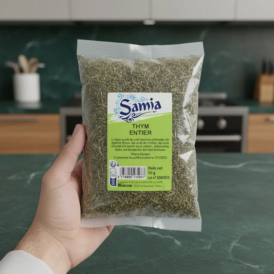 Thym entier SAMIA tenu à la main en cuisine moderne, herbe séchée de qualité pour assaisonnement naturel et intense.