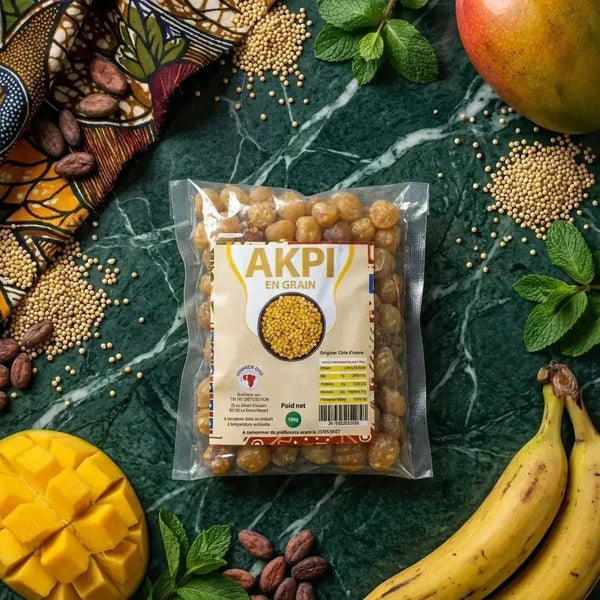 Sachet d'Akpi en grain sur fond marbre vert, avec mangue, bananes, graines de moutarde.