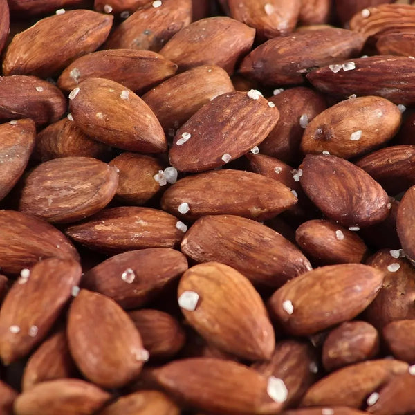 Amandes grillées salées, vue rapprochée. Couleur brune, cristaux de sel visibles.