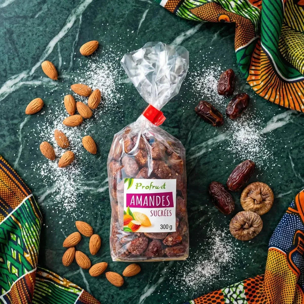 Sacchetto trasparente di mandorle zuccherate Profruit (300g) su sfondo marmorizzato, con mandorle, datteri.