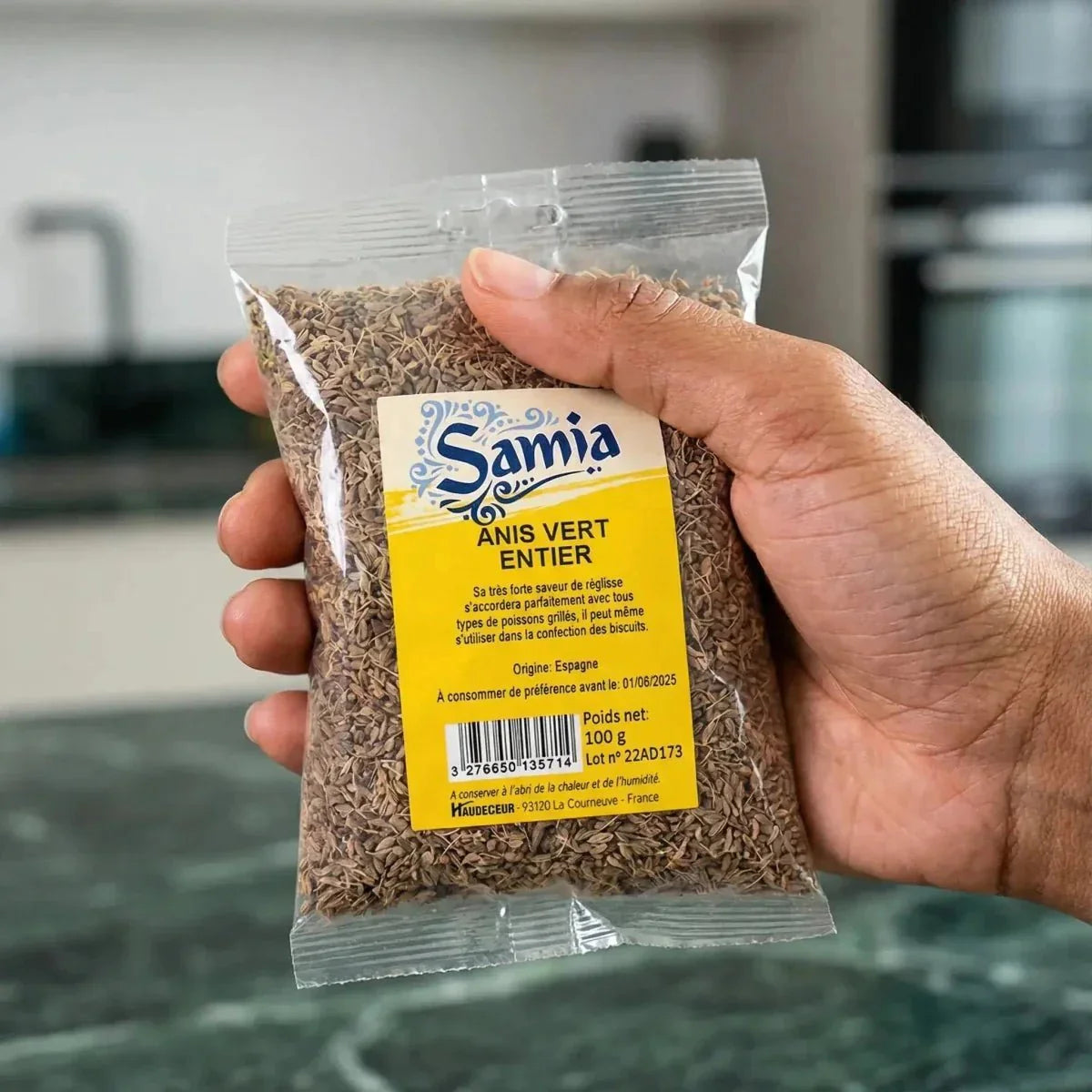 Sachet transparent d'Anis Vert Entier Samia, tenu à la main. Étiquette jaune et bleue.