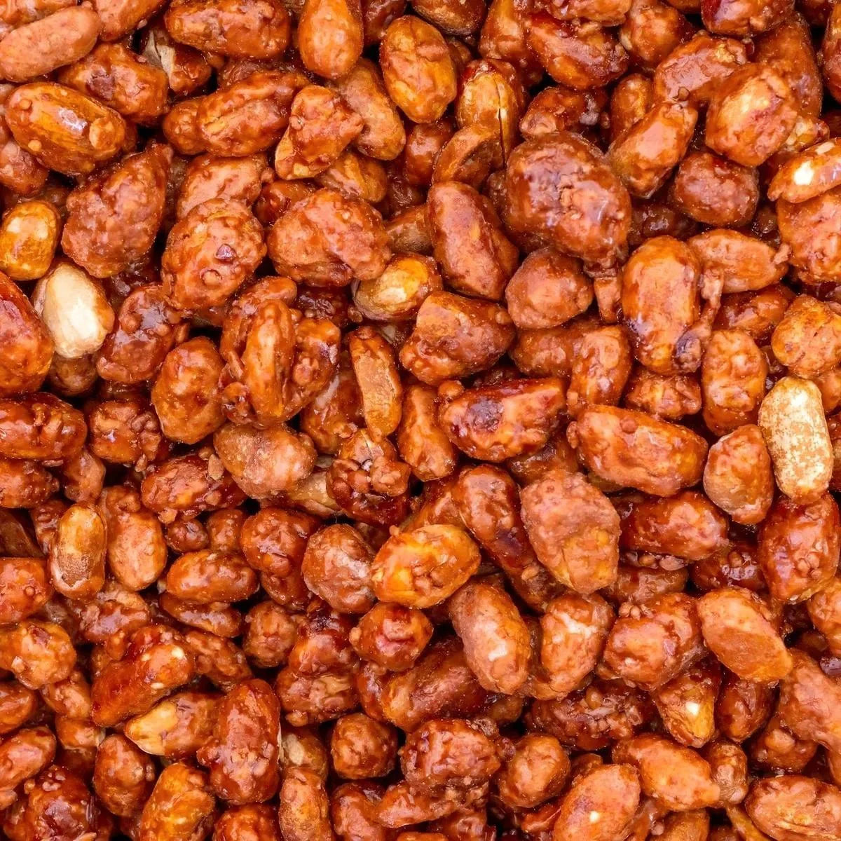 Glanzende gekarameliseerde pinda's, knapperige textuur, intense karamelkleur, smakelijk.