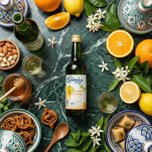 Orangenblütenaroma SAMIA 50cL auf Marmorplatte mit Orangen, Zitronen, Honig, Mandeln.