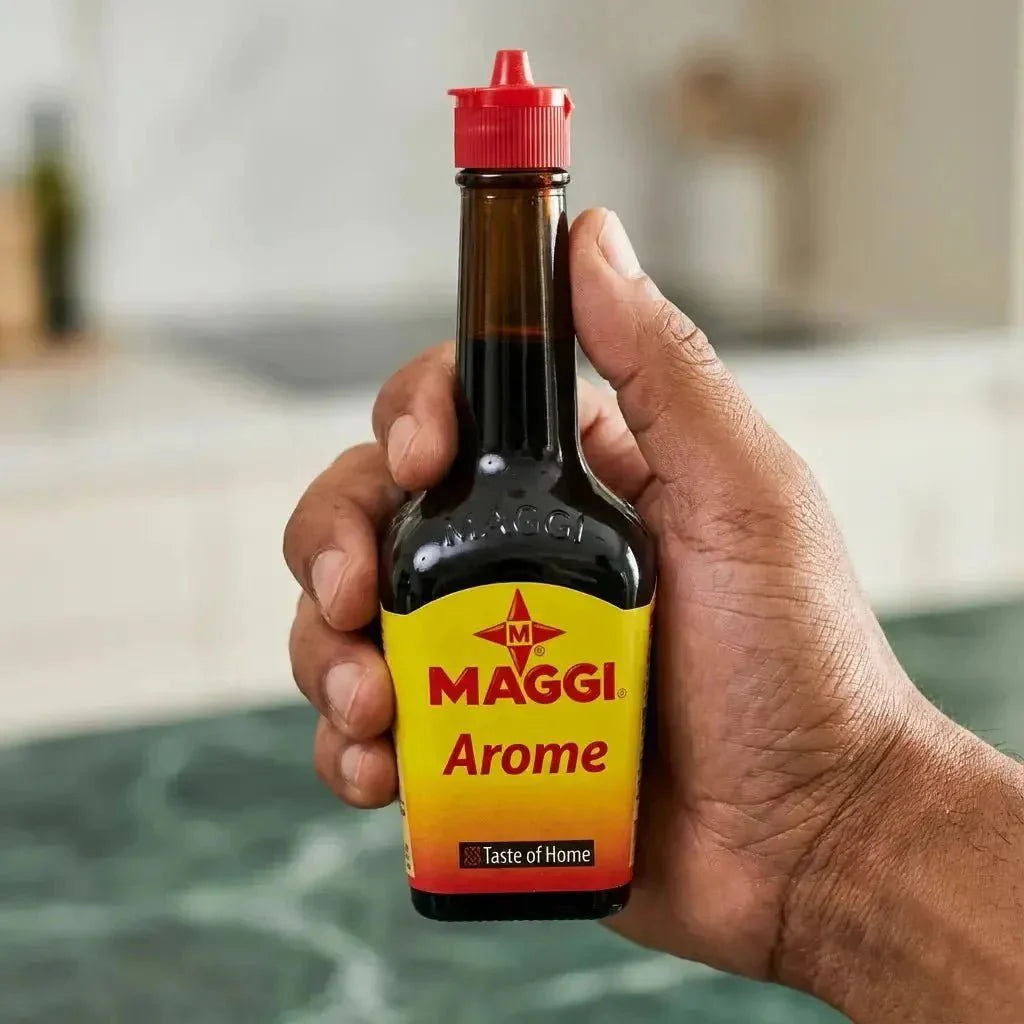 MAGGI flavor bottle held in hand. Glass bottle, yellow-orange label. Red cap.