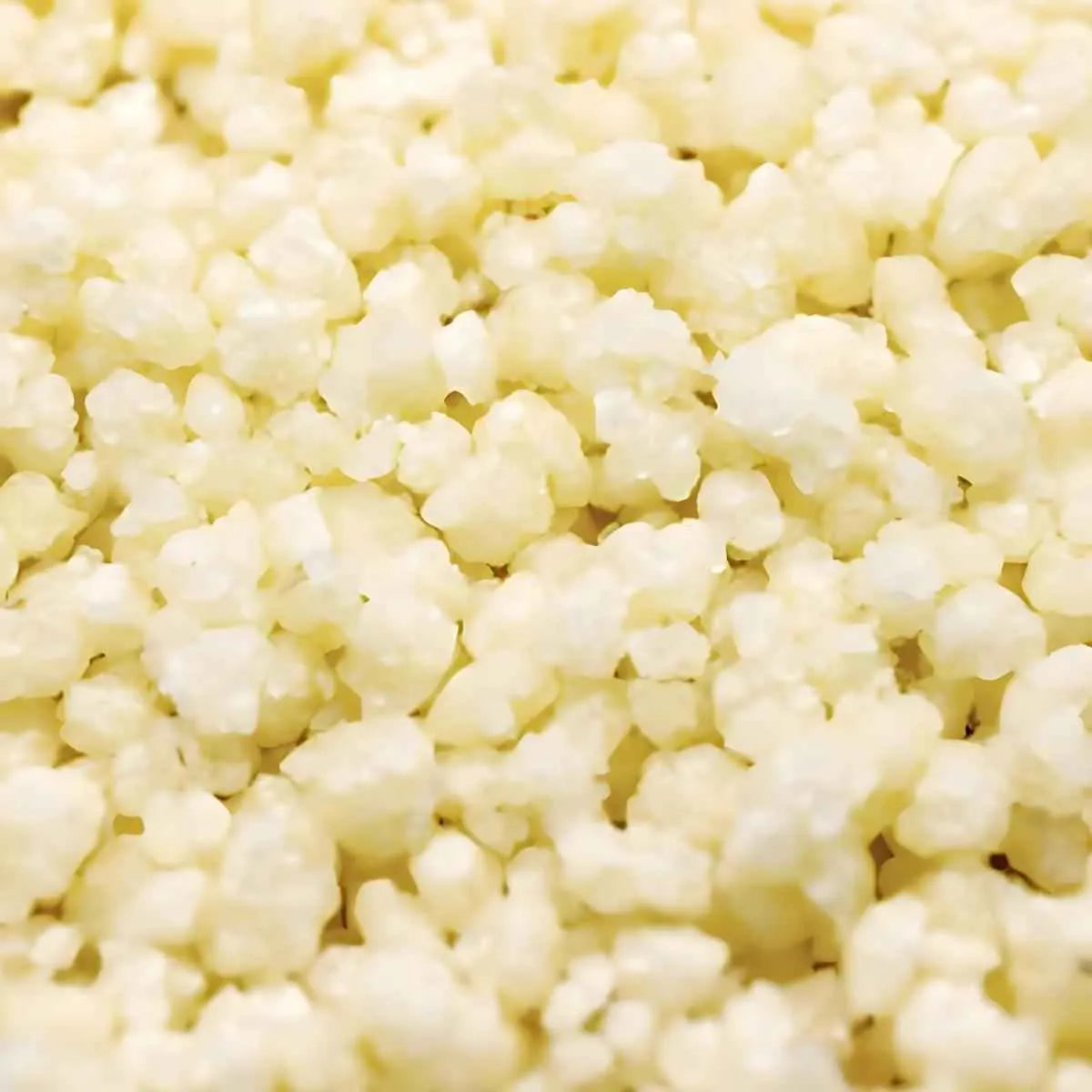 Gros plan sur grains d'Attiéké Sec Marguerite, texture légère et aérée de couscous de manioc. Parfait pour accompagner viandes et poissons.