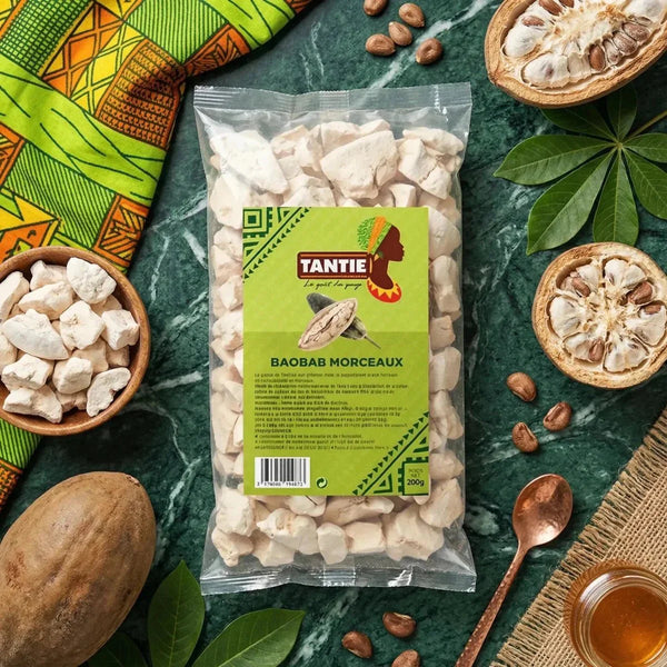 Tüte mit Baobab-Stücken TANTIE auf grün marmoriertem Hintergrund. Holzschale gefüllt, ganze Früchte.