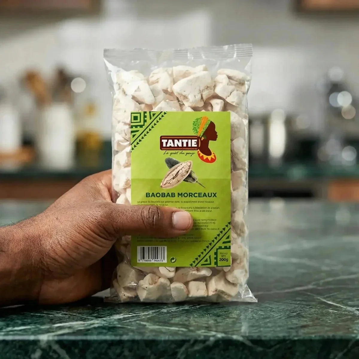 200g bag of TANTIE baobab pieces held by hand on a green marble countertop.