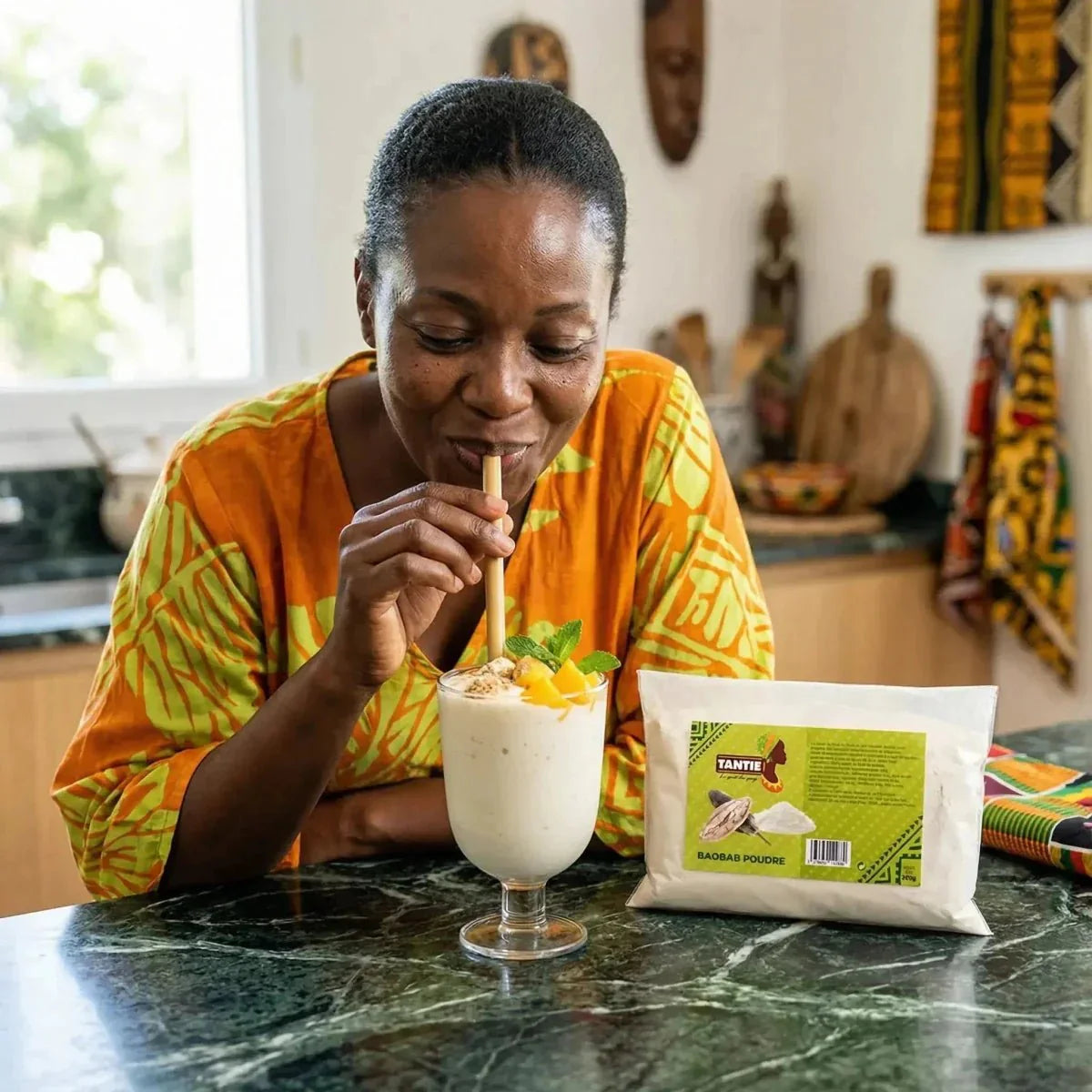 Vrouw die een smoothie drinkt met TANTIE baobabpoeder 200g. Verpakking in wit, groen, geel en zwart.