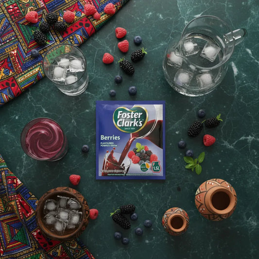 Préparation savoureuse FOSTER CLARKS Jus Poudre Berries sur table avec fruits rouges, verres et pichet d'eau fraîche.