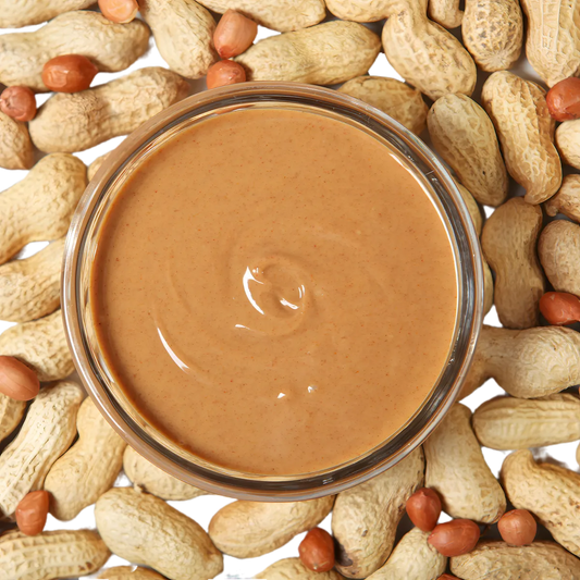 Bol de Beurre de Cacahuète RACINES BIO entouré de cacahuètes entières, mettant en valeur son origine naturelle et bio.