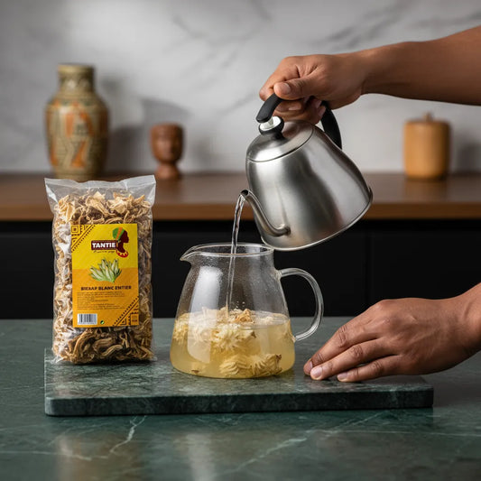 Préparation d'une infusion chaude avec Bissap blanc entier TANTIE, hibiscus séché versé dans une théière en verre sur plan de travail.