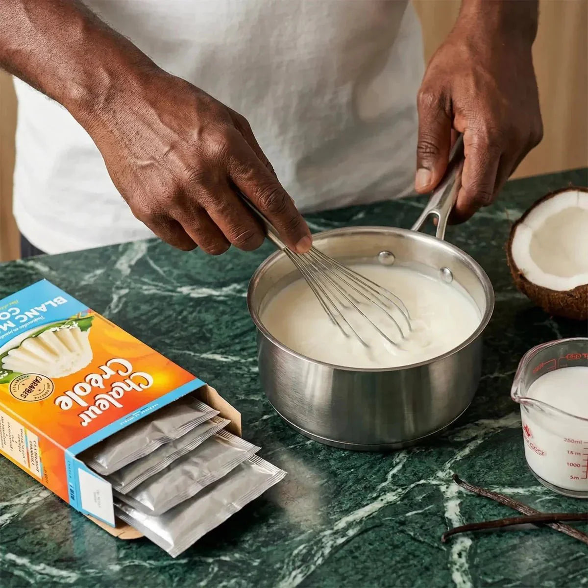 Préparation de blanc manger coco Chaleur Créole. Boîte ouverte avec sachets, casserole, lait.