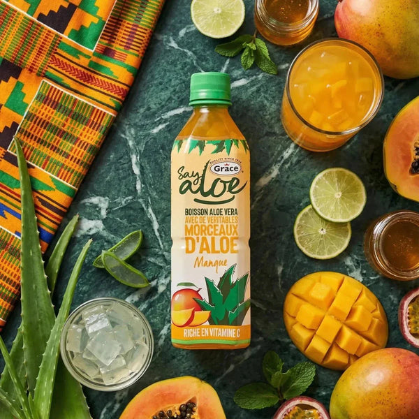 Nahaufnahme einer Flasche Grace Say Aloe Mango, umgeben von tropischen Früchten.