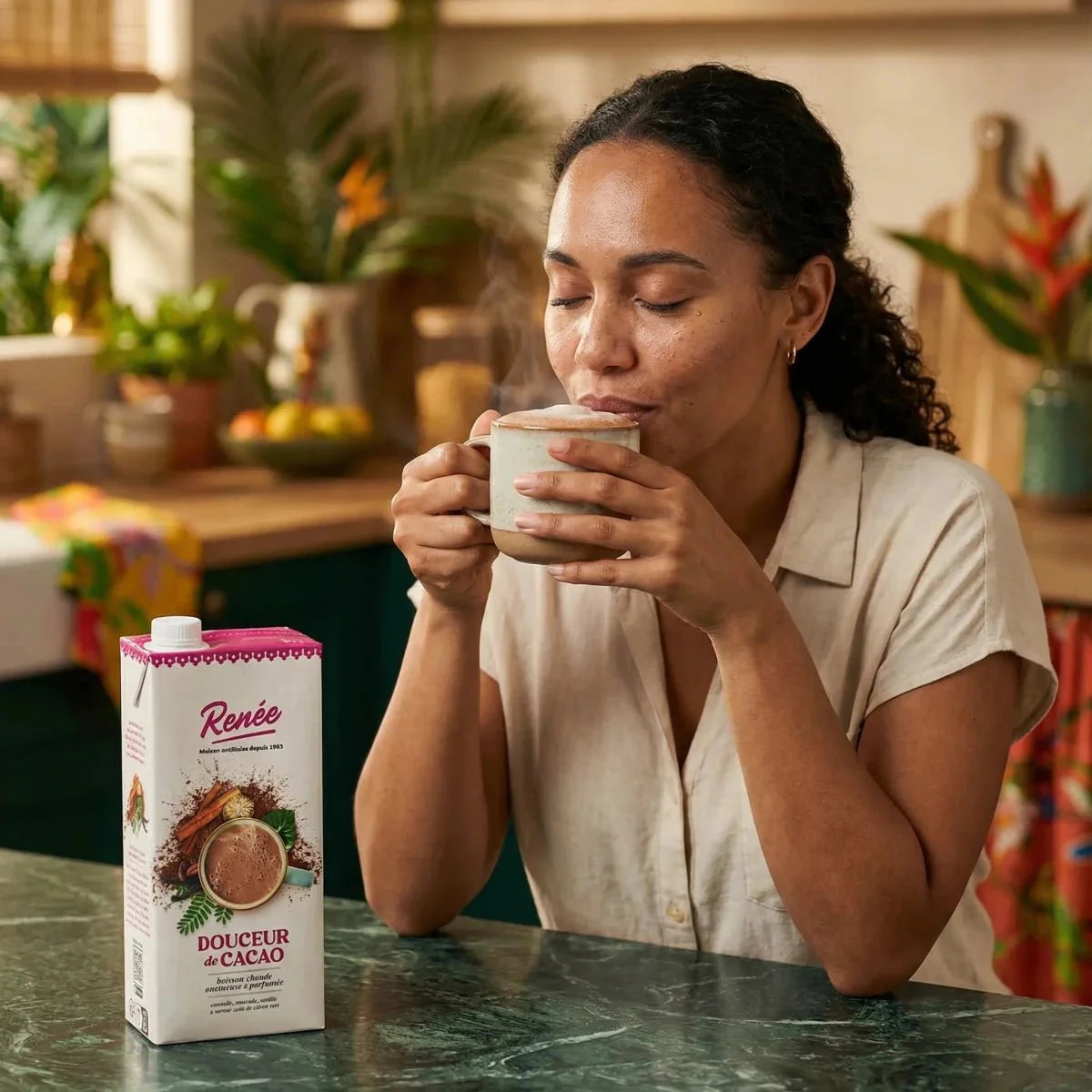 Cacaodrank RENÉE 1L. Vrouw die geniet van een dampend kopje, verpakking zichtbaar. Warme kleuren.
