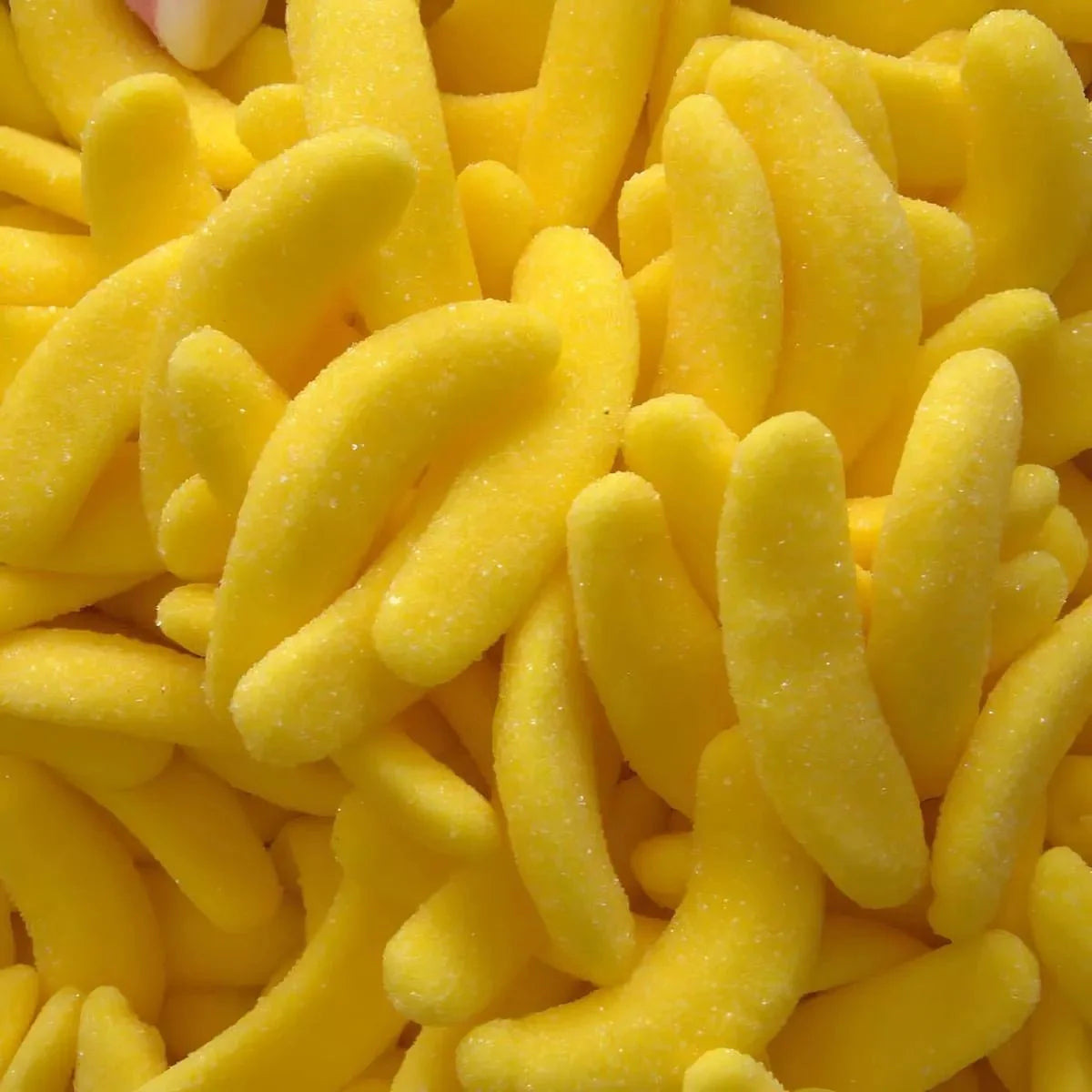 Caramelle alla banana gialla, ricoperte di zucchero. Dolcetti a forma di banana, vista ravvicinata.