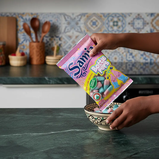 Versement de bonbons halal SAMIA Bottle Pep's dans un bol décoratif, bonbons gélatineux fruités et acidulés en cuisine familiale.