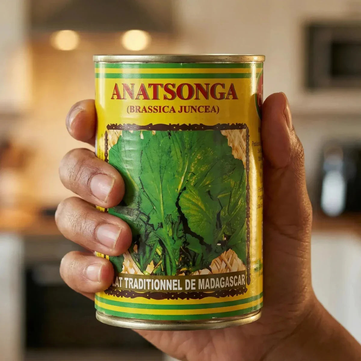 Conserva da 400g di bietole di senape Anatsonga CODAL, tenuta da una mano davanti a una cucina. Giallo.