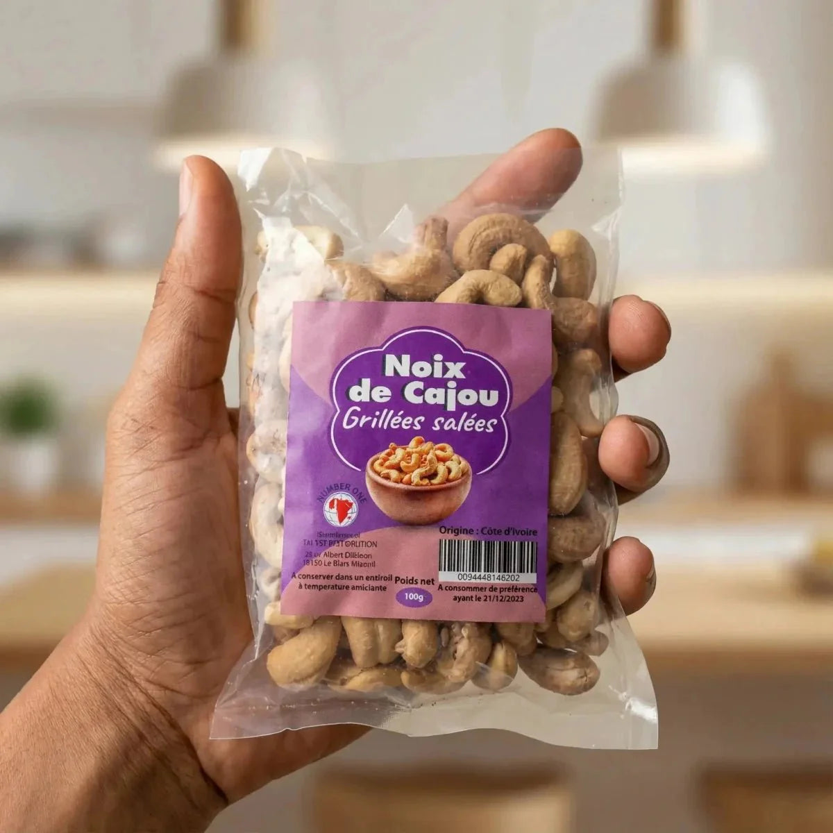 Geroosterde cashewnoten van NUMBER ONE in een doorzichtige zak, vastgehouden in de hand.