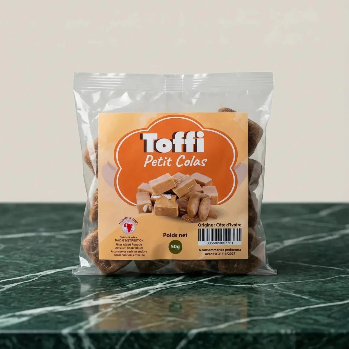 Sachet transparent de caramels "Toffi Petit Colas" sur un comptoir en marbre vert.