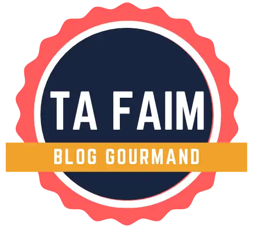 Une badge circulaire avec un bord scallopé, contenant le texte »TA FAIM» et »BLOG GOURMAND».