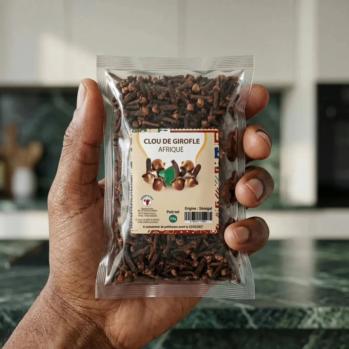 Clou de girofle Afrique de NUMBER ONE, 250g, tenu dans une main. Emballage transparent cuisine.