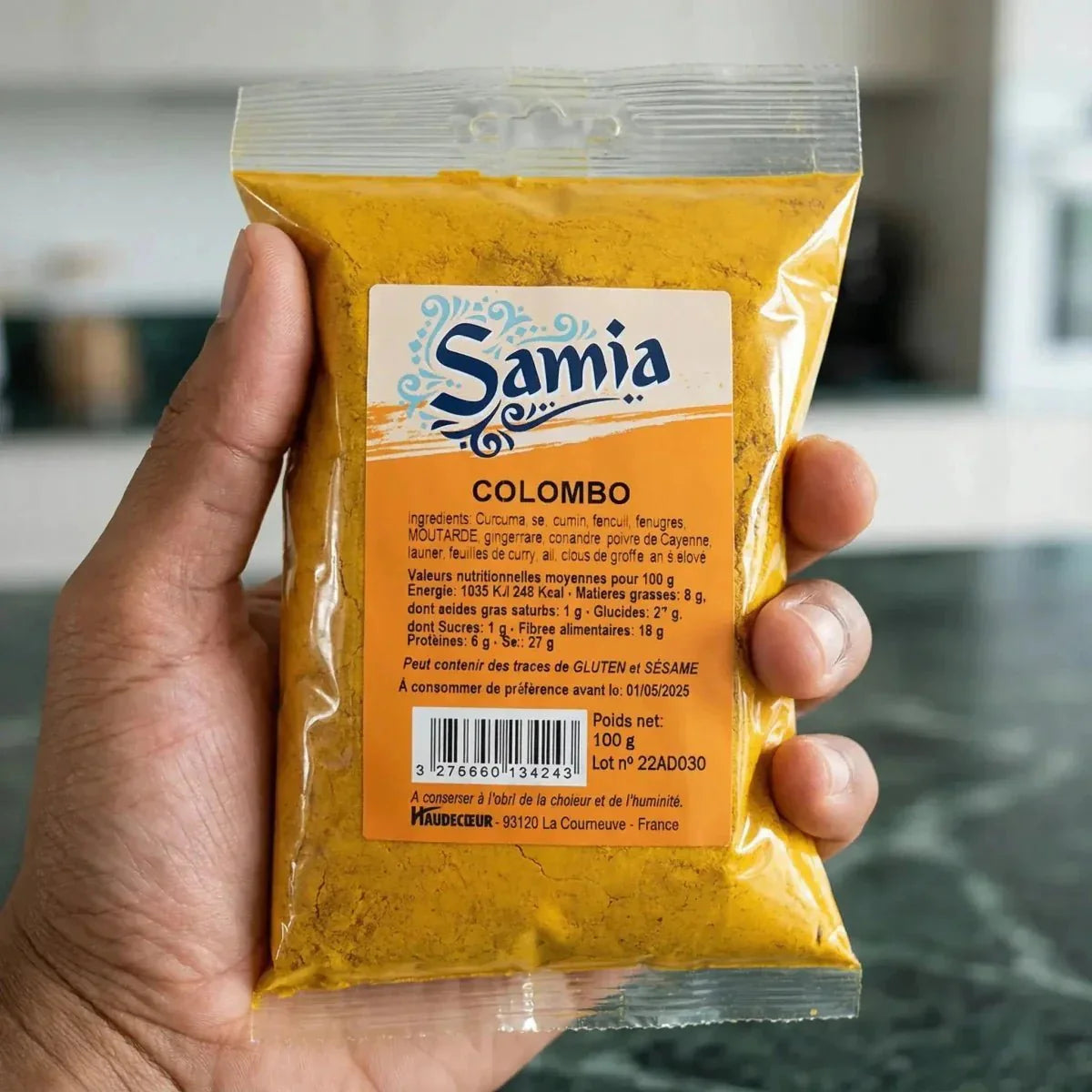 100g SAMIA Colombo-Beutel, in der Hand gehalten, mit Nährwertangaben.