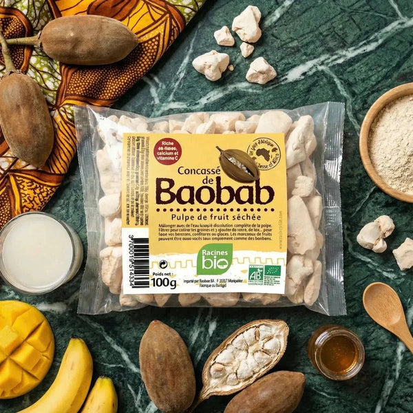 Concassé de baobab BIO RACINES, sachet 100g sur une table avec fruits frais, miel.