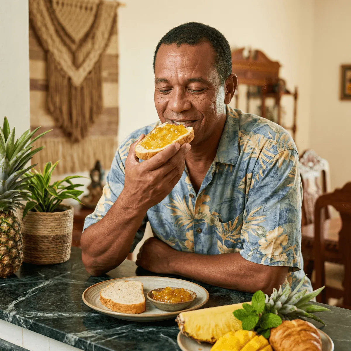 Un uomo gusta una fetta di pane con marmellata di ananas M'AMOUR — 325g, con frutta fresca accanto.