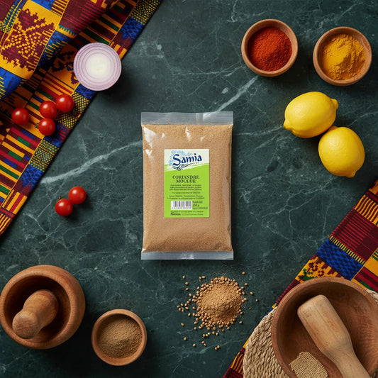 Sachet de coriandre moulue SAMIA entouré d'épices, citrons et ustensiles de cuisine, parfait pour la cuisine traditionnelle et exotique.