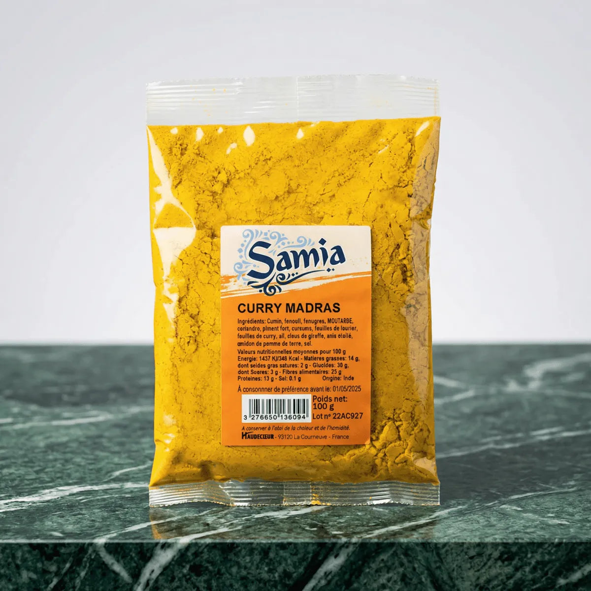 Curry madras, de Samia, en sachet transparent sur un fond vert marbré.
