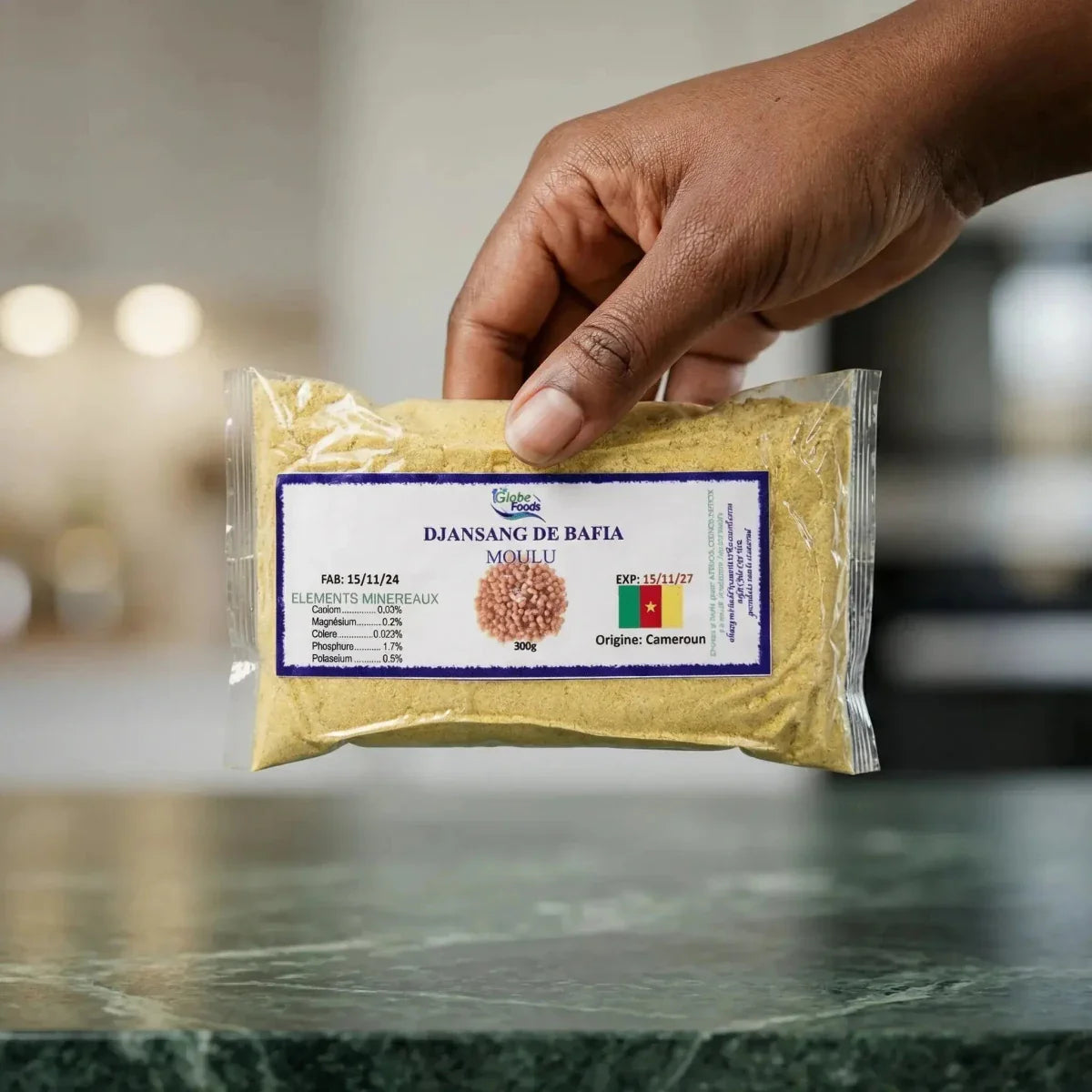 Handgehaltene Tüte Globe Foods mit gemahlenem Djansang aus Bafia auf einer Küchentheke.