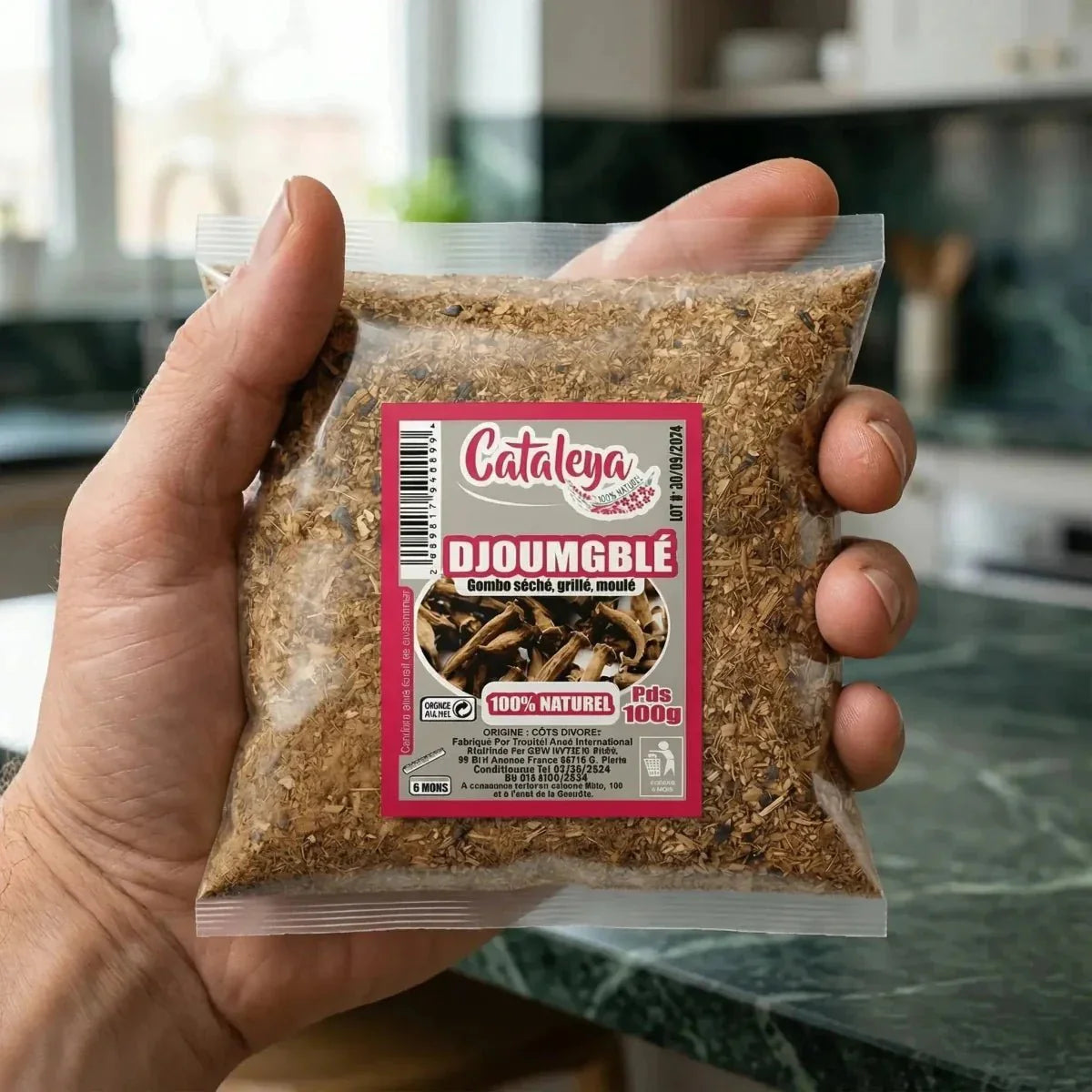 Photo d'un sachet de Djoumblé CATALEYA 100g, tenu à la main dans une cuisine.