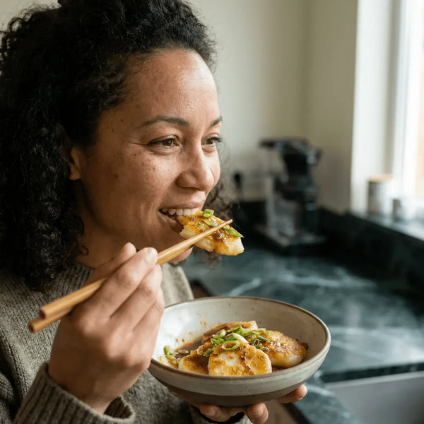 LEGUMOR : Femme mangeant de la farine de riz avec des baguettes. Plat cuisiné dans un bol.